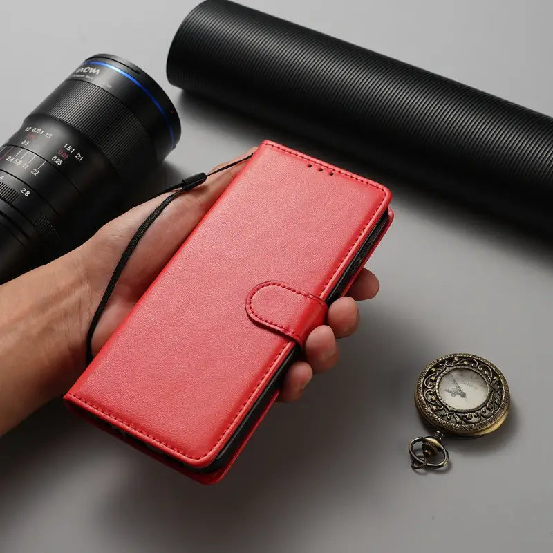 a hand holding a red leather wallet case with a camera and a camera lens
