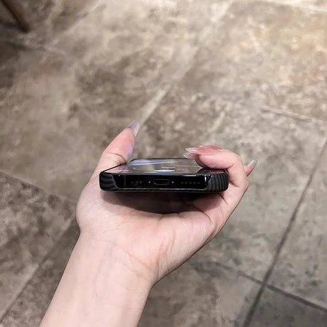 A hand holding a smartphone in a clear case.