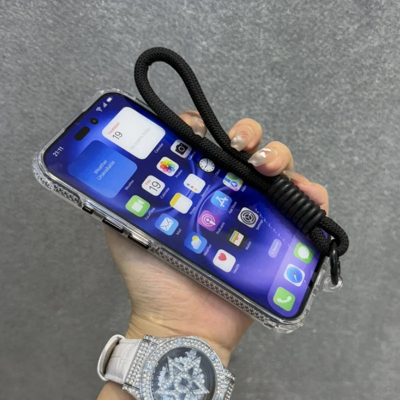 Hand holding a smartphone in a clear case with a black wrist strap.