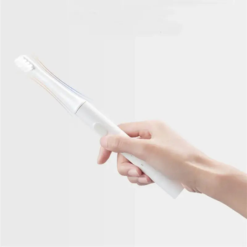 A hand holding a white and blue toothbrush