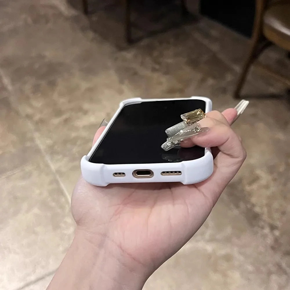 Hand holding a white smartphone with long, ornate fingernails.