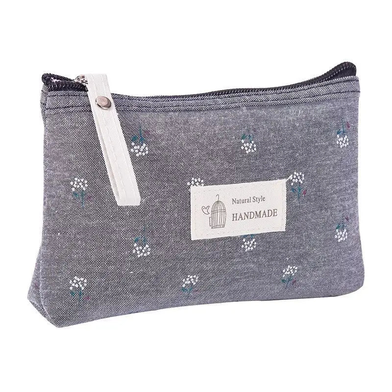 the small pouch bag is made from a denim fabric with a small white flower pattern