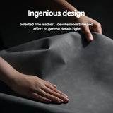 Hands demonstrating the pliability and texture of dark grey leather.