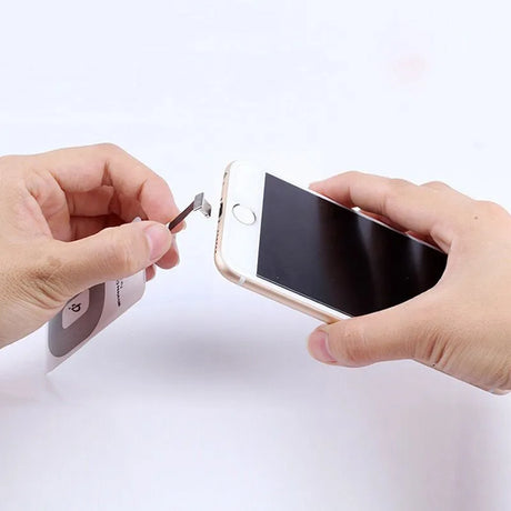 Hands using a tool to remove or install a smartphone’s SIM card.