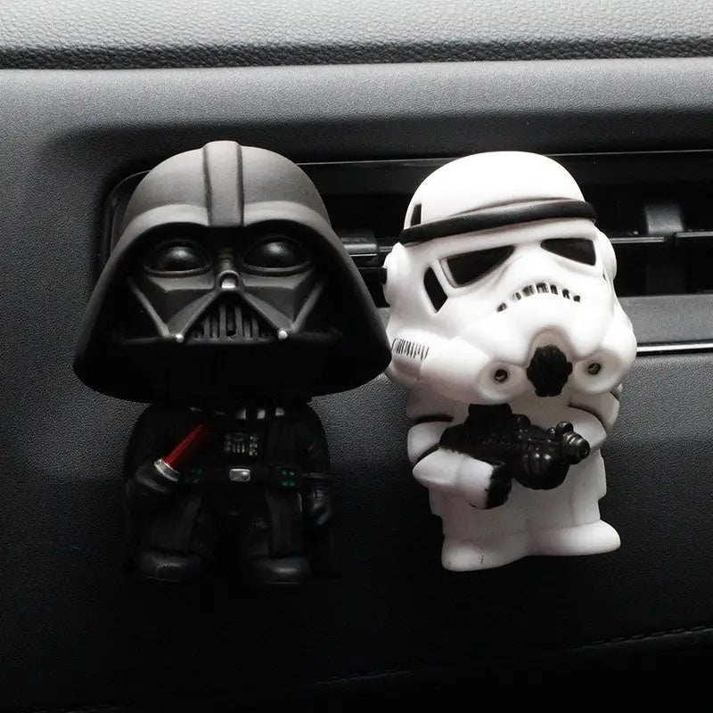 two star wars sit on the dashboard of a car