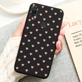 a woman holding a phone case with pink hearts on it