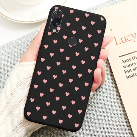 a woman holding a phone case with pink hearts on it