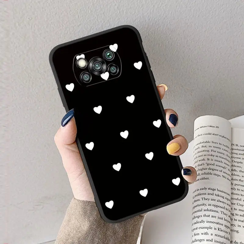 a woman holding a phone case with white hearts on it