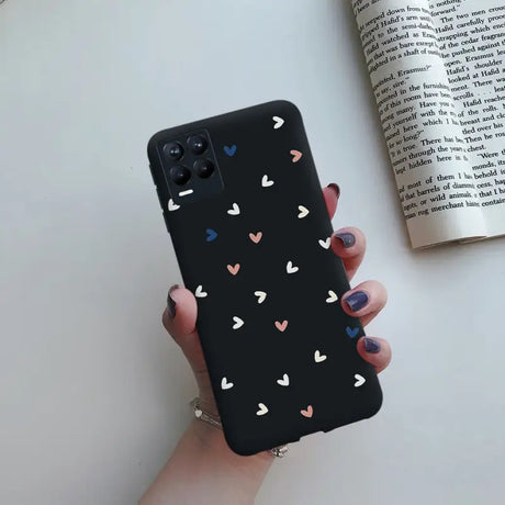 a woman holding a black phone case with hearts on it