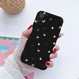 a woman holding a phone case with hearts on it