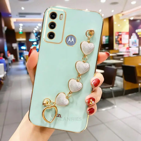 a woman holding a phone case with heart charms