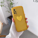 a woman holding a yellow phone case with a heart on it