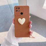 a woman holding a brown phone case with a heart