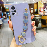 a woman holding a phone case with heart charms