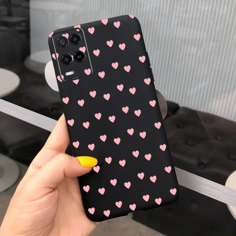a hand holding a phone case with pink hearts on it