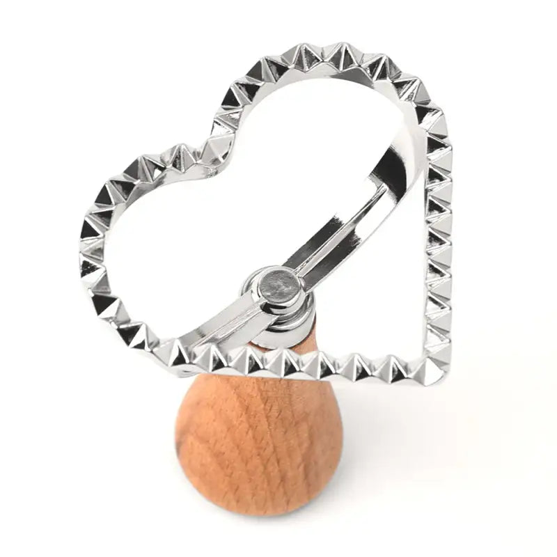a heart shaped cookie cutter with a wooden handle