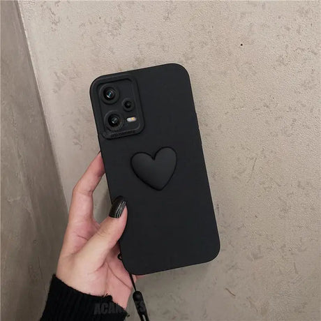 a hand holding a black iphone case with a heart on it