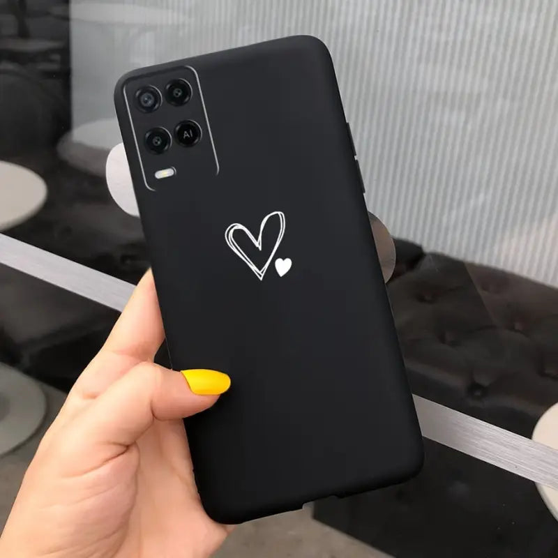 a hand holding a black phone with a heart sticker on it