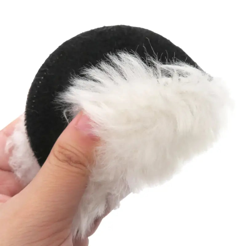 a hand holding a small black and white toy