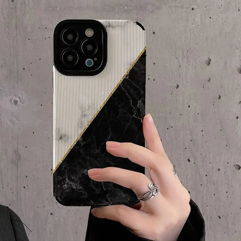 someone holding a phone up to take a picture of a black and white marble case