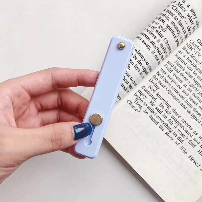 a hand holding a blue bookmark with a book open