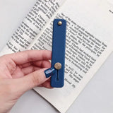 a hand holding a blue bookmark with a bookmark in the background