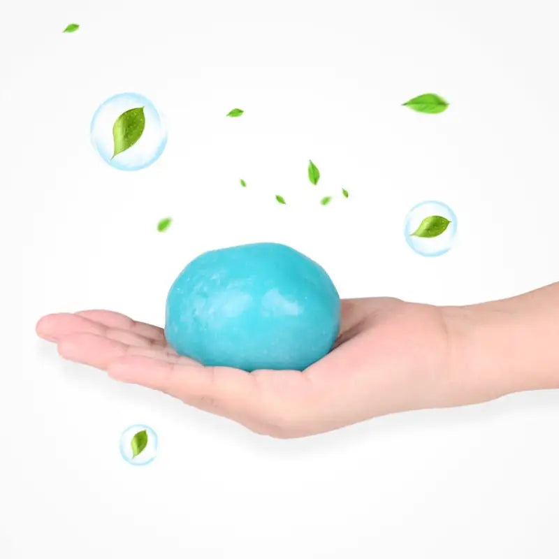 a hand holding a blue ball with leaves flying around it