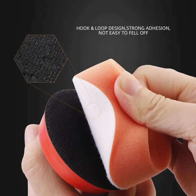 a hand holding a foam ball with a black and orange surface