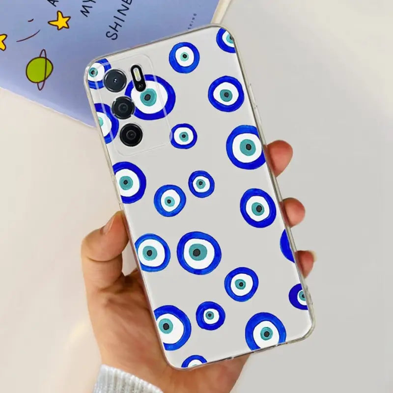 a hand holding a phone case with blue eyes