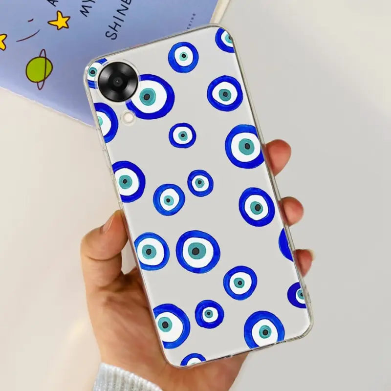 a hand holding a phone case with an evil eye pattern