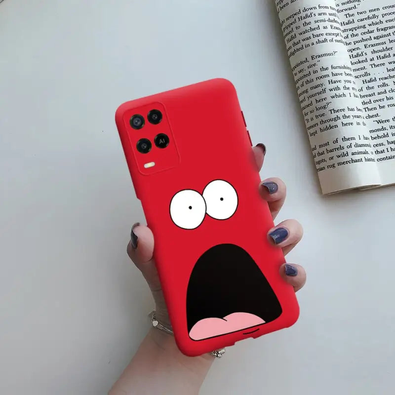 a hand holding a red phone case with a cartoon face