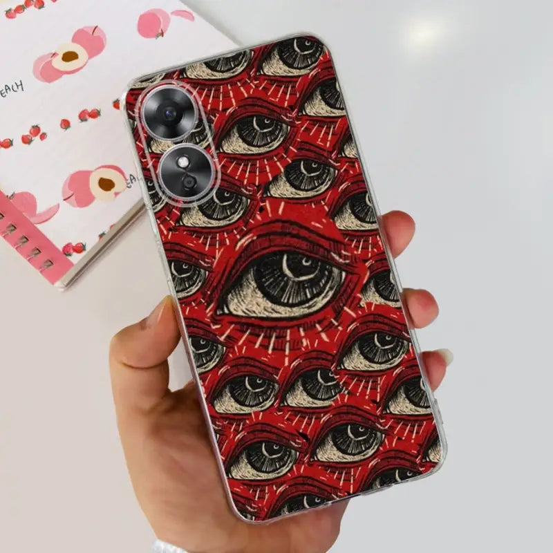 a hand holding a red phone case with an eye pattern