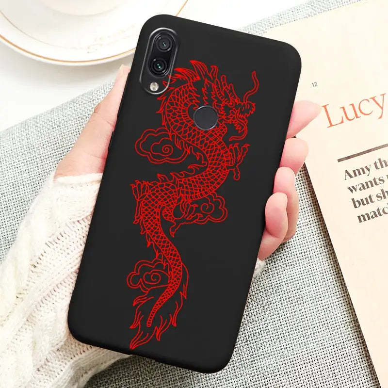 a hand holding a phone case with a red dragon on it