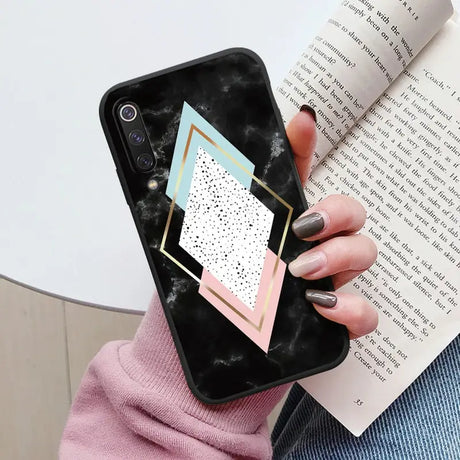 a woman holding a phone case with a geometric design