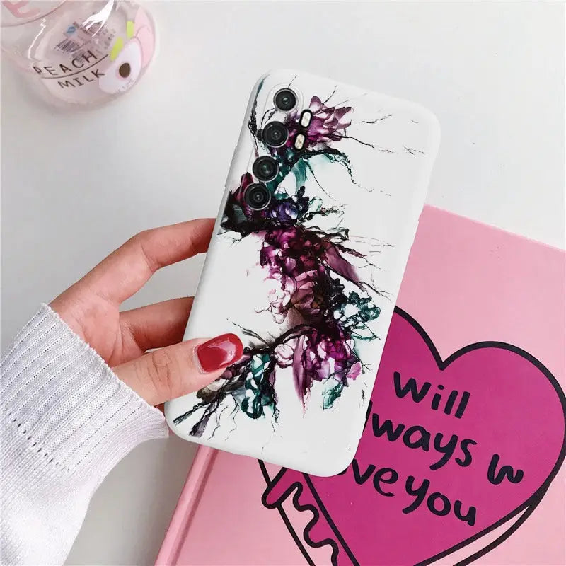 a hand holding a phone case with a heart painted on it