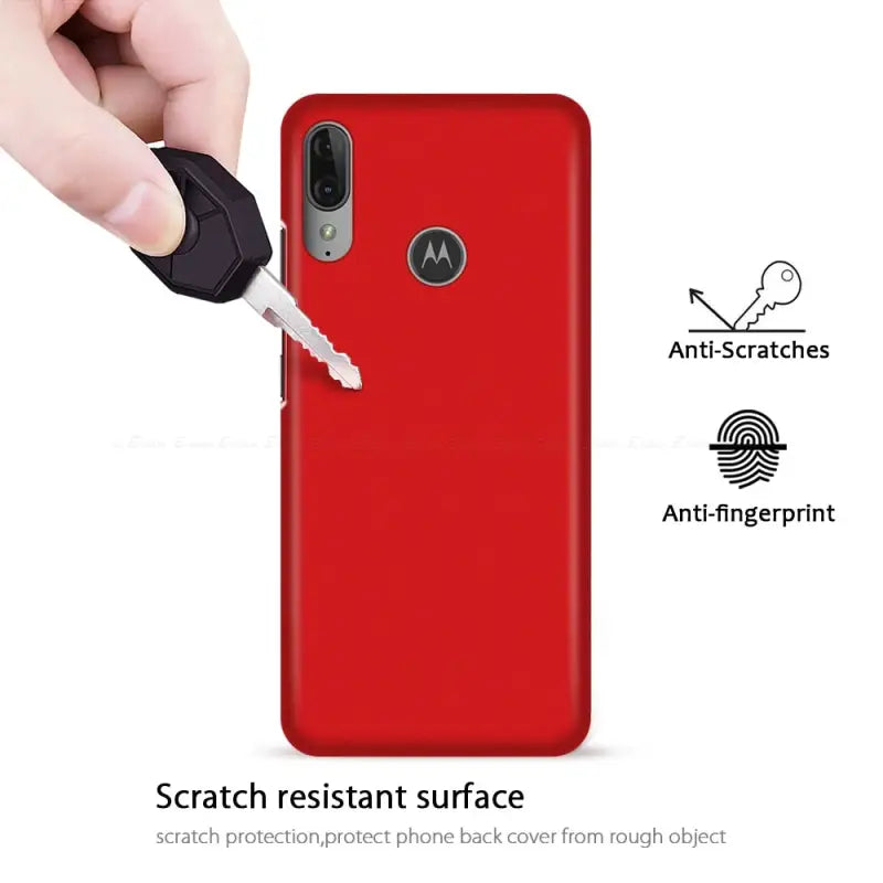 a hand holding a key to a red motorola phone