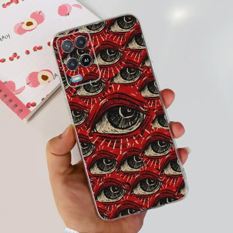 a hand holding a red phone case with an eye pattern