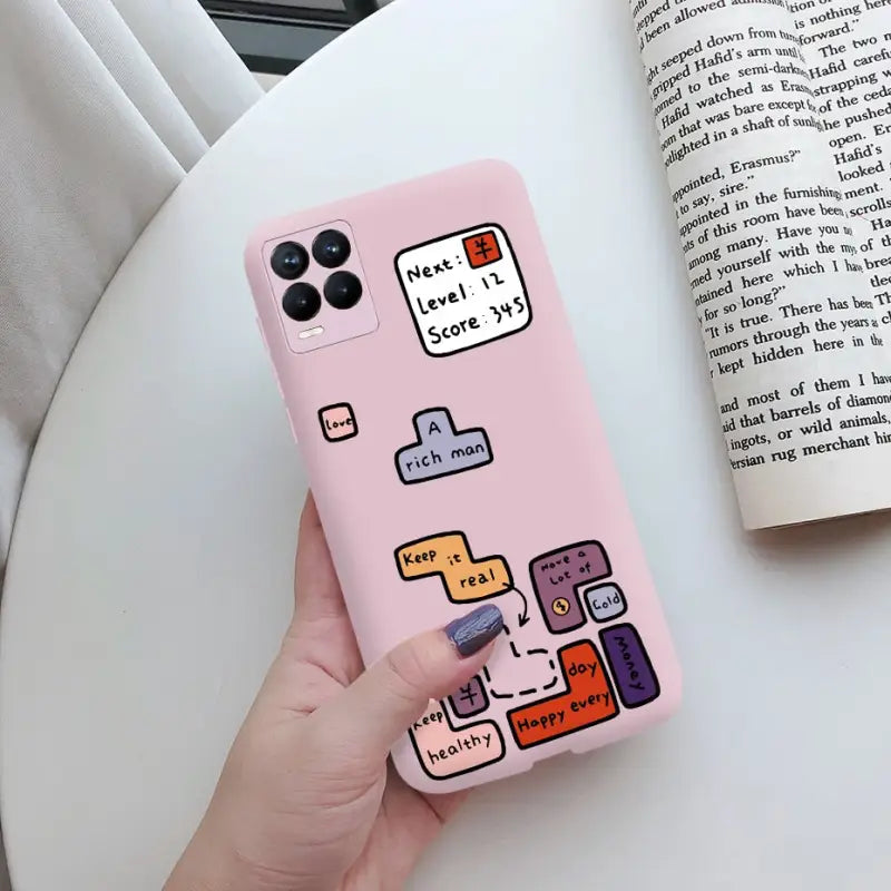 a hand holding a pink phone case with a book and a book