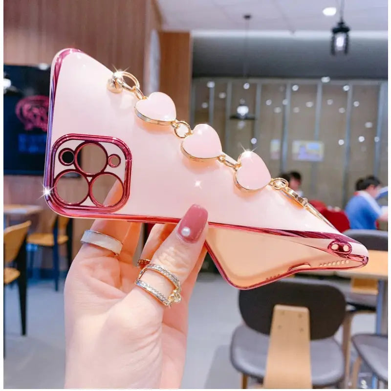 a hand holding a pink phone case with a heart design