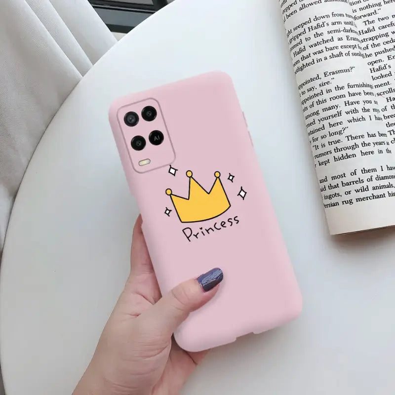a hand holding a pink phone case with a crown on it