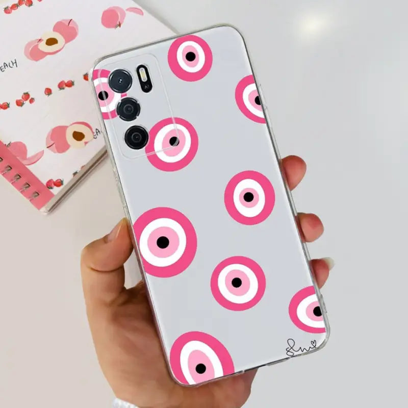a hand holding a pink phone case with a pink eye pattern