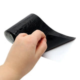 a hand holding a roll of black vinyl