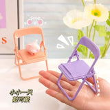 a hand holding a small chair with a small pig
