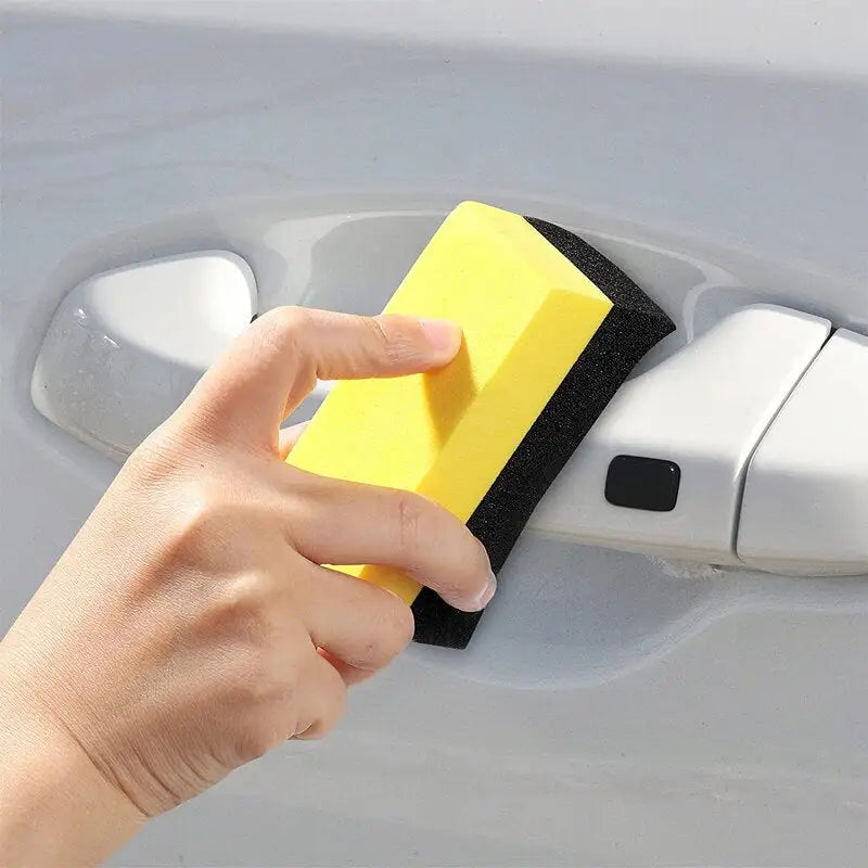 a hand holding a sponge to a car