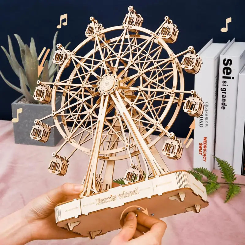 someone is holding a wooden model of a ferris wheel
