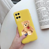 a hand holding a yellow phone case with a teddy bear