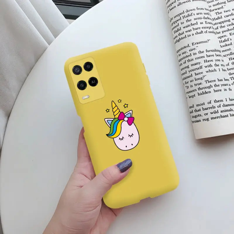 a hand holding a yellow phone case with a unicorn on it
