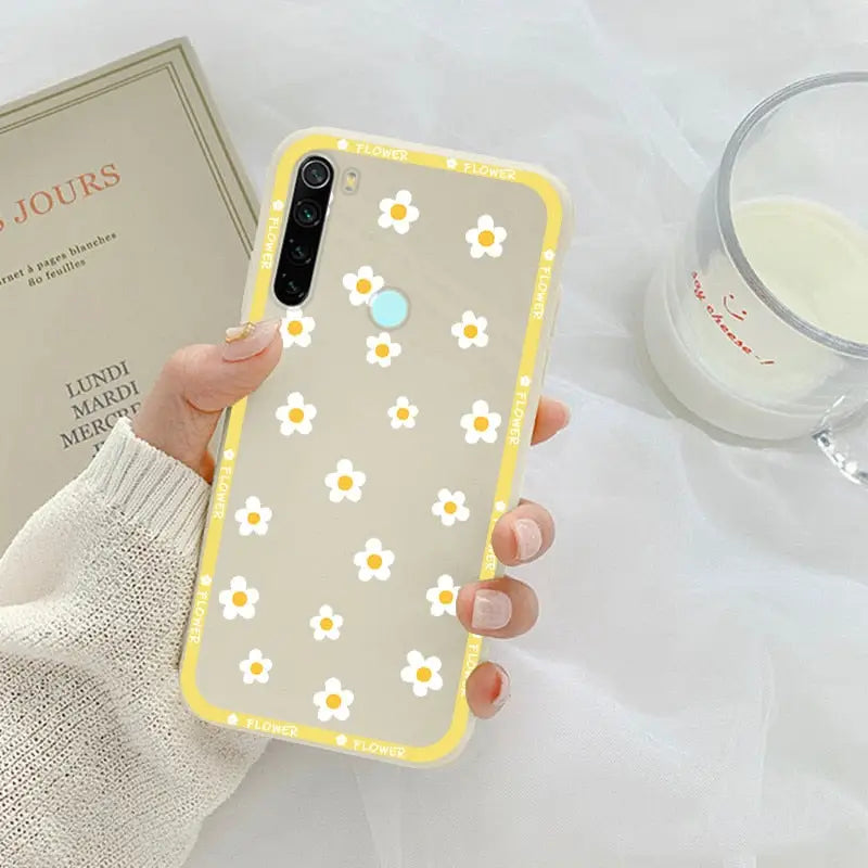 someone holding a yellow and white iphone case with a flower design