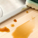 a person is cleaning a wooden surface with a sponge