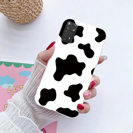 a woman holding a phone case with a cow print